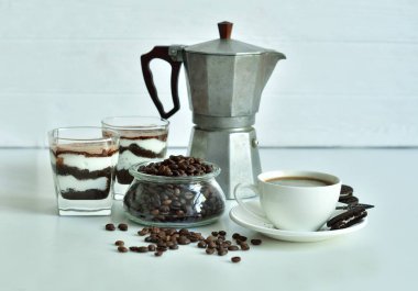 Bir fincan sade kahve ve kahve çekirdeği, bardakta tatlı. Çikolatalı cheesecake ve beyaz arka planda süzme peynir kremi. Günaydın konsepti. Uzayı kopyala Seçici odak.