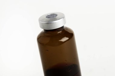 Kehribar rengi aşı enjeksiyon şişesinin seçici odak noktası beyaz arka planda olan makro bir çekim..