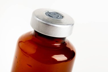 A macro shot with selective focus of an amber color vaccine injection bottle set on a plain white background. clipart