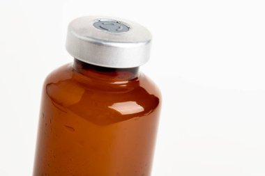 Kehribar rengi aşı enjeksiyon şişesinin seçici odak noktası beyaz arka planda olan makro bir çekim..