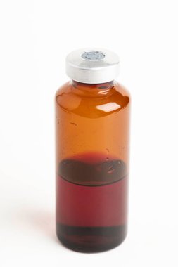 Kehribar rengi aşı enjeksiyon şişesinin seçici odak noktası beyaz arka planda olan makro bir çekim..