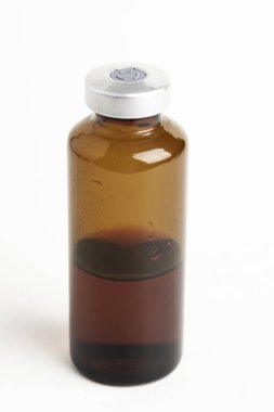 Kehribar rengi aşı enjeksiyon şişesinin seçici odak noktası beyaz arka planda olan makro bir çekim..