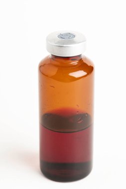 Kehribar rengi aşı enjeksiyon şişesinin seçici odak noktası beyaz arka planda olan makro bir çekim..