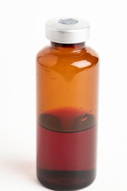 Kehribar rengi aşı enjeksiyon şişesinin seçici odak noktası beyaz arka planda olan makro bir çekim..