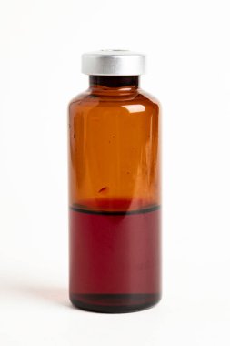 Kehribar rengi aşı enjeksiyon şişesinin seçici odak noktası beyaz arka planda olan makro bir çekim..