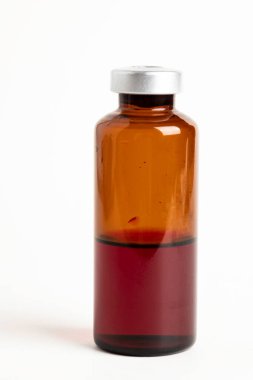 Kehribar rengi aşı enjeksiyon şişesinin seçici odak noktası beyaz arka planda olan makro bir çekim..