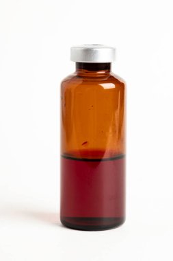 Kehribar rengi aşı enjeksiyon şişesinin seçici odak noktası beyaz arka planda olan makro bir çekim..