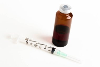 Hijyenik, tek kullanımlık plastik, tek kullanımlık, kehribar renkli ilaç enjeksiyonunun beyaz bir arka planda yakın plan çekimi..