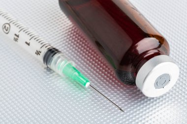 Hijyenik, tek kullanımlık plastik, tek kullanımlık, metal arka planda kehribar renkli bir ilaç enjeksiyonunun yakın çekim görüntüsü..