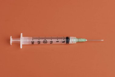 Kırmızı arka planda tek kullanımlık tek kullanımlık plastik enjeksiyon setinin seçici odak noktasıyla yakın çekim..