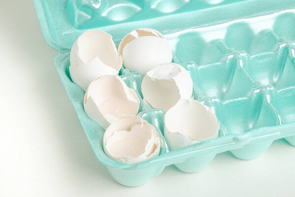Крупный план набора растрескавшихся белых яиц, отдельно расположенных на ядрах подноса из пенопласта.
