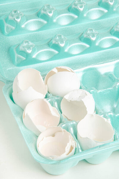 Крупный план набора растрескавшихся белых яиц, отдельно расположенных на ядрах подноса из пенопласта.