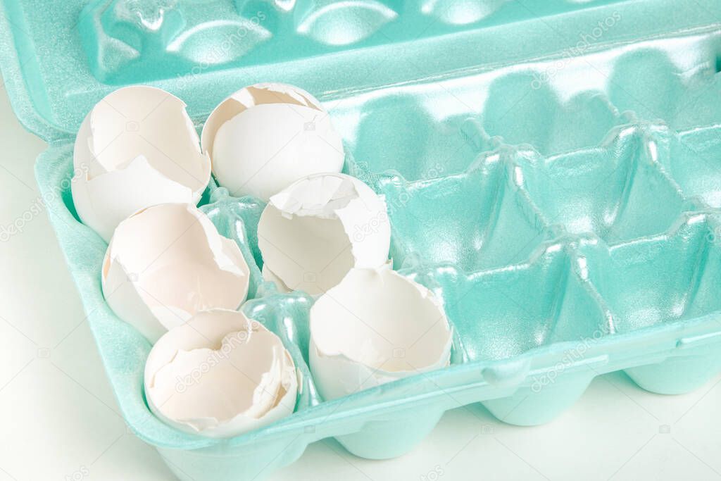 A close-up of a set of cracked white egg shells individually nestled on cores of styrofoam tray.