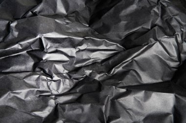 Arkaplan resmi olarak buruşmuş siyah kağıdın desenli ve gölgeli bir arazisi.