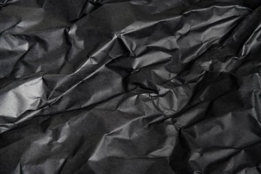 Arkaplan resmi olarak buruşmuş siyah kağıdın desenli ve gölgeli bir arazisi.