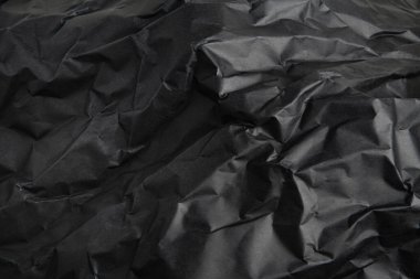 Arkaplan resmi olarak buruşmuş siyah kağıdın desenli ve gölgeli bir arazisi.