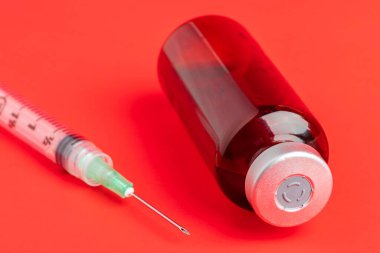 A close-up shot of an hygienic single-use plastic disposable syringe injection with amber color vial set on red background. clipart