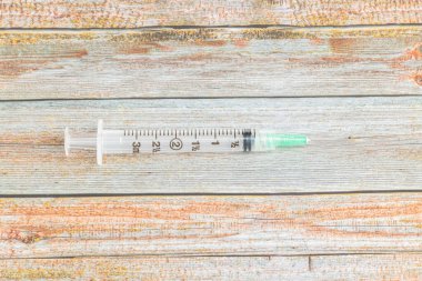 Tahta desenli arka planda tek kullanımlık tek kullanımlık plastik enjeksiyon enjeksiyonunun seçici odak noktası olan yakın çekim..