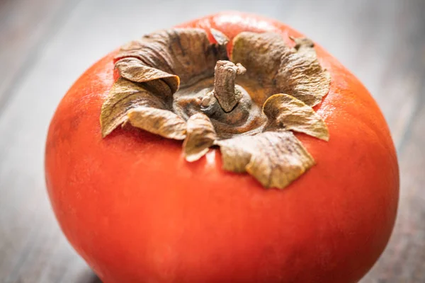 木のテーブルに熟した柿の実をセットしたマクロショット — ストック写真