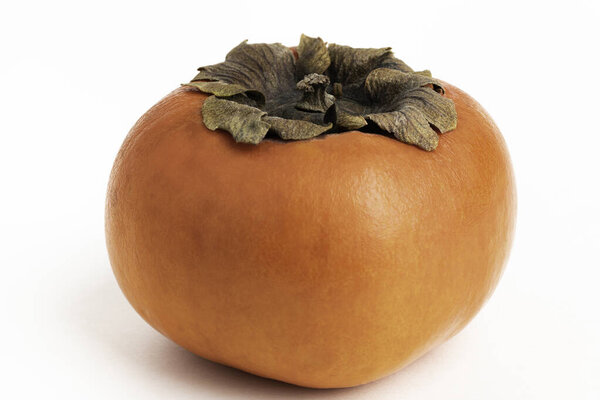 Close-up shot with shallow depth of field of a ripe persimmon fruit set on a plain white background.