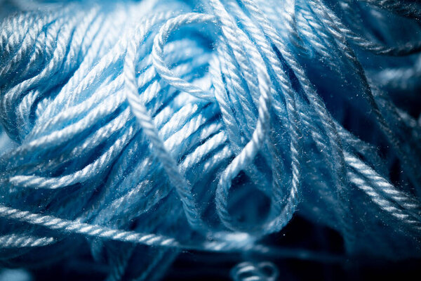An extreme close-up with selective focus of blue and fuzzy bundled crochet threads.