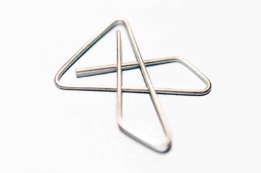 An extreme macro shot with selective focus of an x-style silver metal paper clip set on white background. clipart
