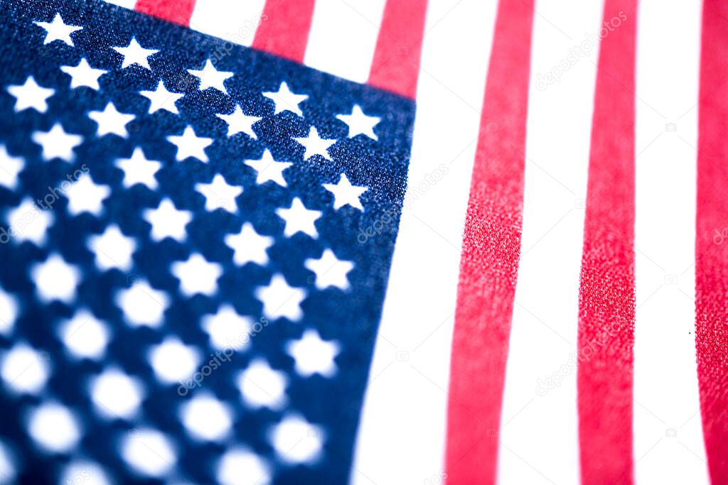 A macro shot with selective focus of a small handheld American flag on coarse fabric.