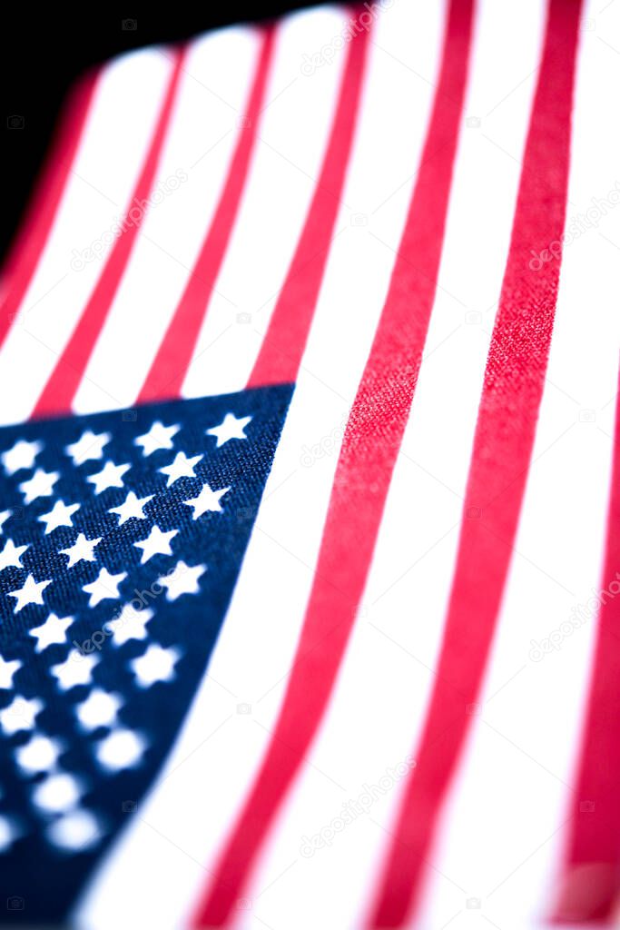 A macro shot with selective focus of a small handheld American flag on coarse fabric.