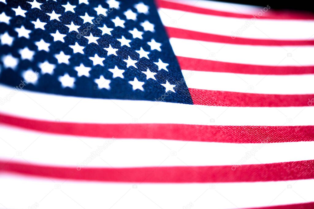 A macro shot with selective focus of a small handheld American flag on coarse fabric.