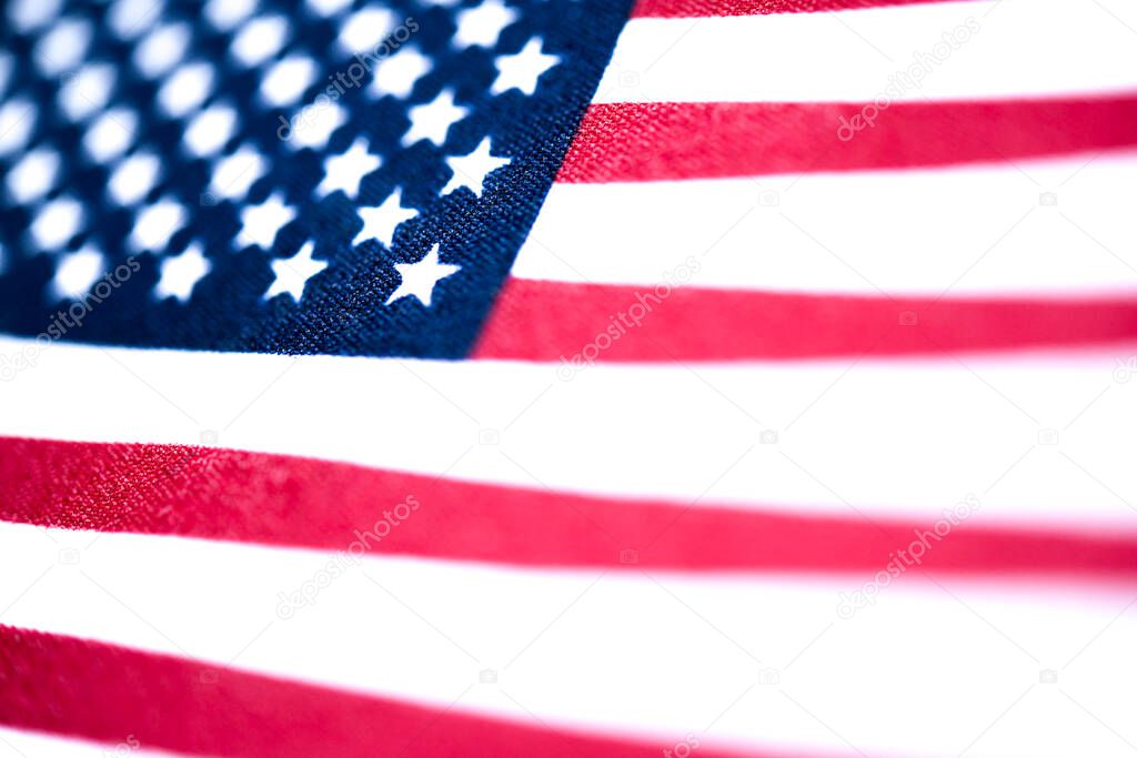 A macro shot with selective focus of a small handheld American flag on coarse fabric.