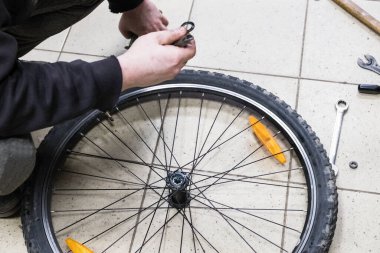 A mechanic repairs a bicycle wheel. The adjustment is great for operation. Spoked wheel with inflated tires. Bicycle repair workshop.