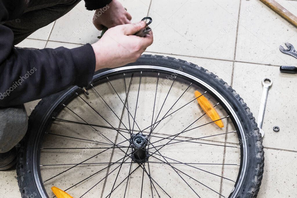 A mechanic repairs a bicycle wheel. The adjustment is great for operation. Spoked wheel with inflated tires. Bicycle repair workshop.