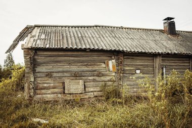 Eski, terk edilmiş bir ahşap ev. Rusya 'da terk edilmiş bir köy. İnsansız bir kulübe. Çürük duvar inşaatı. Mavi gökyüzünün arka planına yaslan. Karelia. - Rusya. Gün.