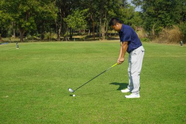 Akşam golf sahasında golf oynayan bir golfçü. Güneşin altında golf oynayan bir adam..                                