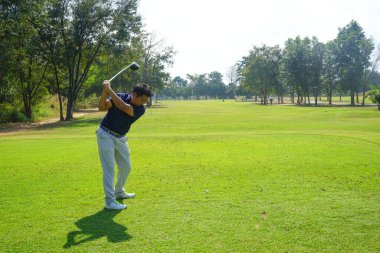 Akşam golf sahasında golf oynayan bir golfçü. Güneşin altında golf oynayan bir adam..                                