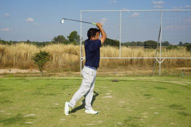 Akşam golf sahasında golf oynayan bir golfçü. Güneşin altında golf oynayan bir adam..                                