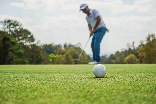 ブルーゴルファーは 緑のゴルフにボールを入れて 太陽のセットの夜の時間にレンズフレア 長い穴にゴルフボールを入れて後に勝つためにゴルファーのアクション — ストック写真