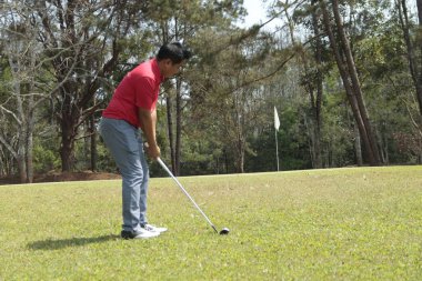 Akşam golf sahasında golf oynayan bir golfçü. Güneşin altında golf oynayan bir adam..