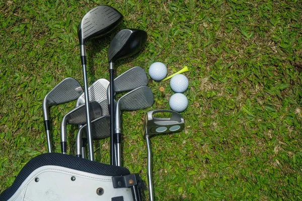 Closeup old golf bags on green. Set of golf clubs over green field background.