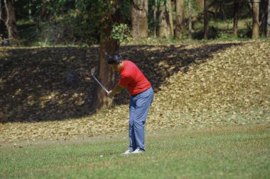 Golfçü golf oynuyor ve yeşil çimen dağ arka planına vuruyor. Asya 'lı erkek oyuncu yazın vuruldu. Spor tatil yaşam tarzı konsepti.                               