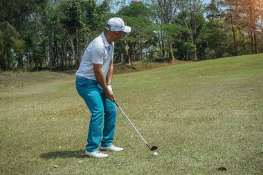 Golfçü golf oynuyor ve yeşil çimen dağ arka planına vuruyor. Asya 'lı erkek oyuncu yazın vuruldu. Spor tatil yaşam tarzı konsepti.                            