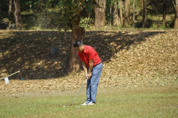 ゴルファーは ゲームゴルフをプレイしていると緑の草の山の背景に行く打撃 アジアの男性選手のゲームは夏に撮影した スポーツの休日のライフスタイルコンセプト — ストック写真