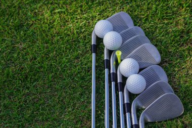 Golf ekipmanları. Yeşil çimlerde golf ve golf sopası. Yeşil çimlerin üzerinde duran golf ekipmanları koleksiyonu. Açık hava sporu.                                