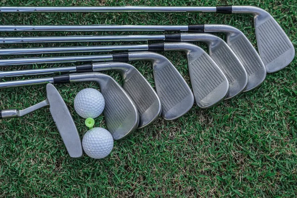 Golf equipment. Golf ball and golf club on green grass background. Collection of golf equipment resting on green grass. Outdoor sport.