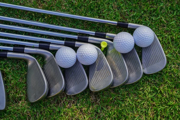 Golf equipment. Golf ball and golf club on green grass background. Collection of golf equipment resting on green grass. Outdoor sport.