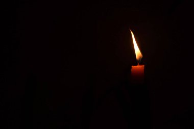 Arka planda mumların ışığı. Mum alevi siyah bir arkaplanda kapanıyor.                               