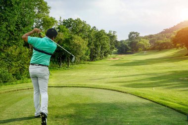 Akşam golf sahasında golf oynayan bir golfçü. Erkek profesyonel golfçü gün boyunca güzel bir sahada golf oynuyor..                               