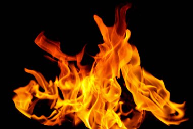 Siyah arka planda yangın alevleri. Doğal ormandaki yangın, alevler ve kıvılcımlar arka planda karanlık bir yakıt, siyah bir arka planda ışıklar.