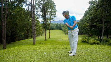 Akşam golf sahasında golf oynayan bir golfçü. Güneşin altında golf oynayan bir adam..                                