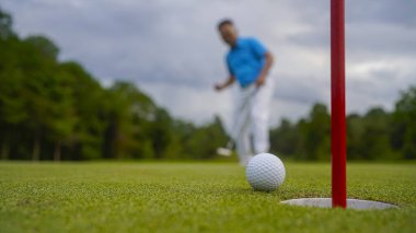 Golf topu yeşil çimlerin üzerinde sabah güneşli güzel bir golf sahasında. Golf topu, bayrak direğiyle deliğin yanındaki golf sahasında..                                